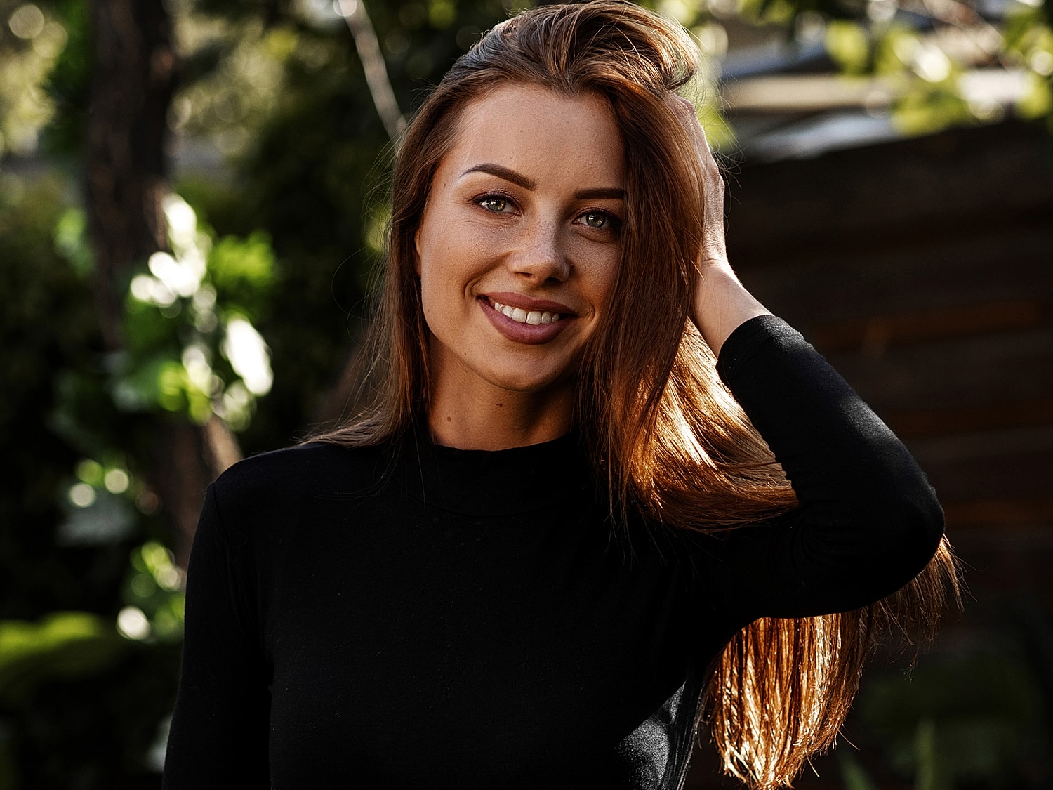 Woman smiling outdoors with long, flowing hair.