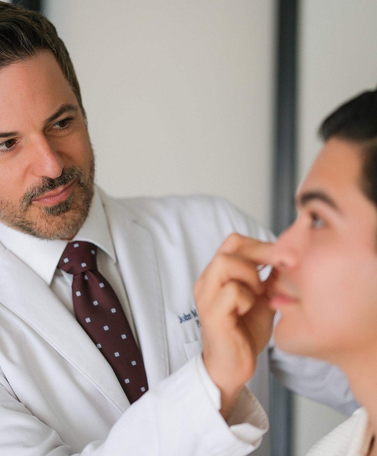 Doctor examining patient’s face in clinic.