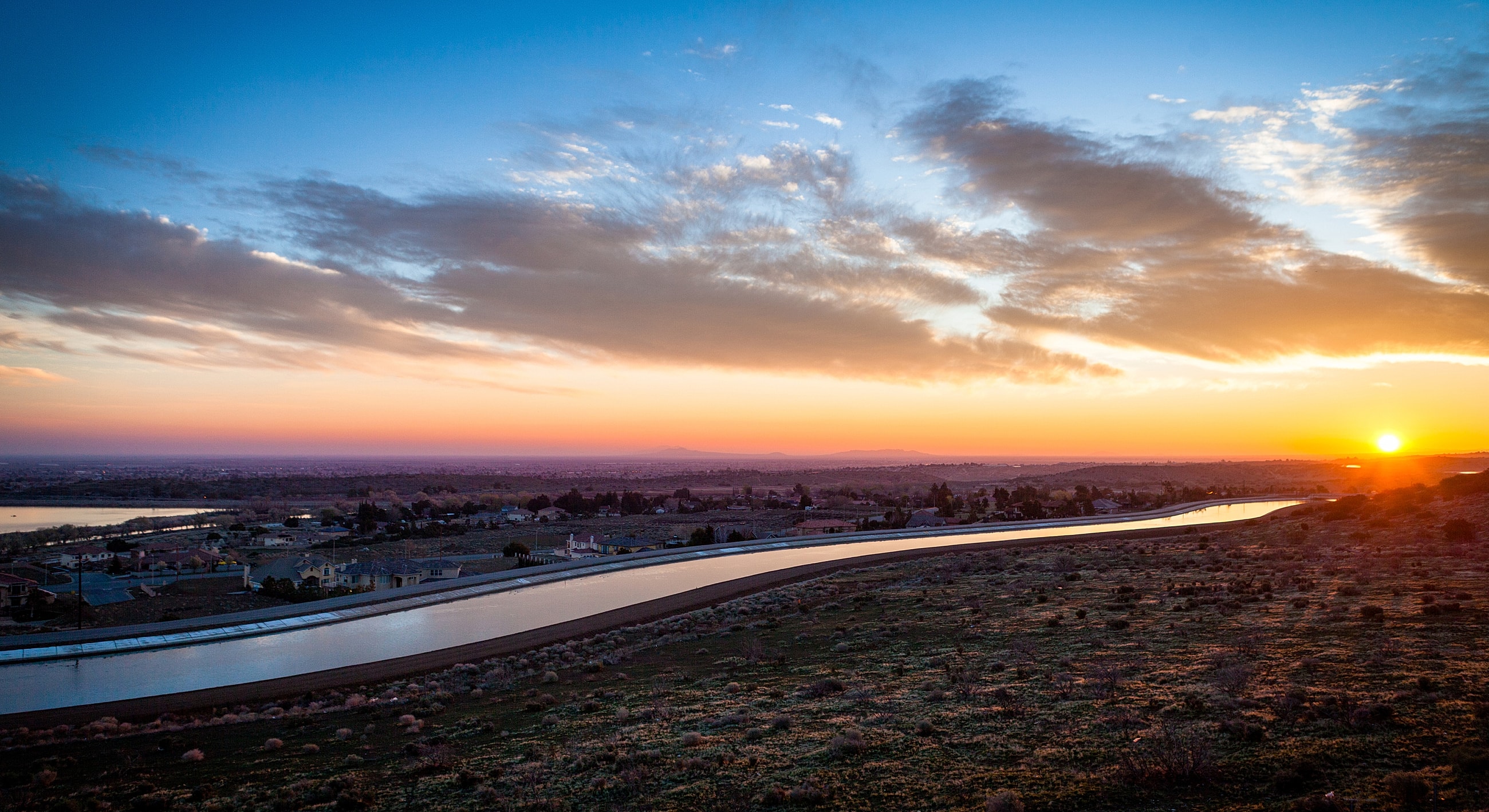Sunrise over landscape with river and clouds.